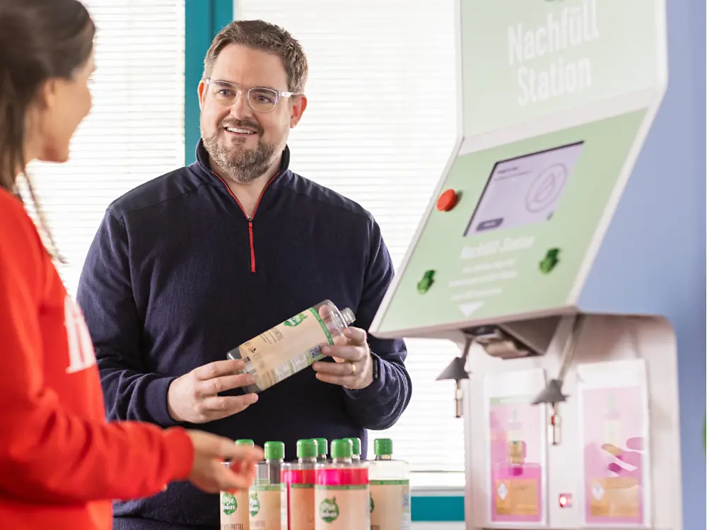 Zamestnanec spoločnosti Henkel stojí pri automate na dopĺňanie tekutín kozmetickej značky Love Nature.