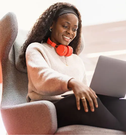 Orryana, zamestnankyňa spoločnosti Henkel, sedí v pohodlnom kresle s laptopom na kolenách