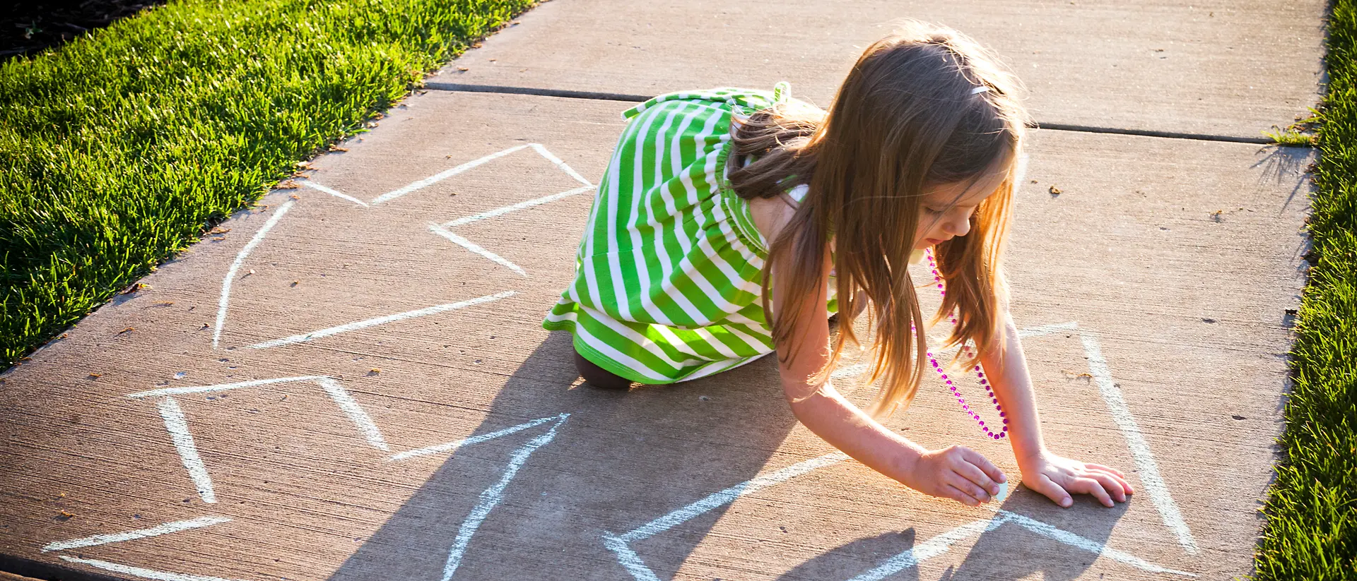 girl in green-white dress painting arrows on a way with chalk
