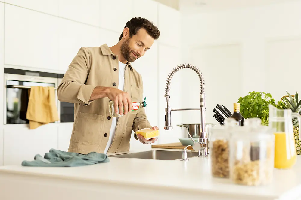 Muž v kuchyni při mytí nádobí