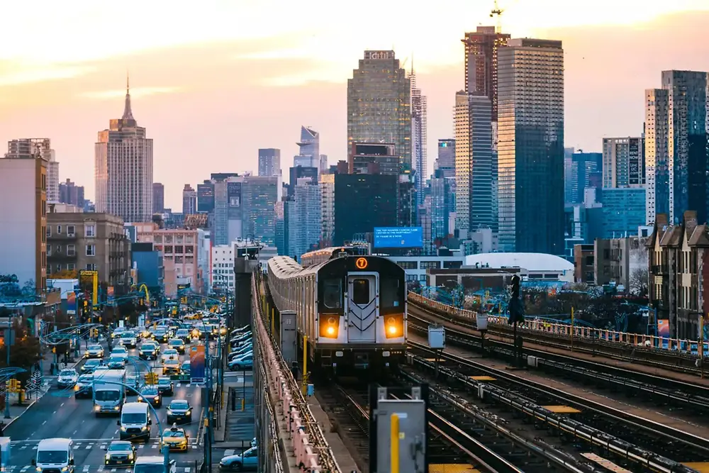 Městský vlak projíždějící moderním městským panoramatem během dne.