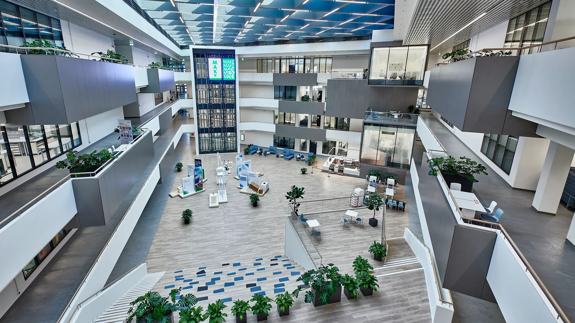 Pohled do interiéru Inspiračního centra v Düsseldorfu s velkým nádvořím uprostřed. Na obrázku jsou také vidět high-tech laboratoře se skleněnými průčelími na celkem čtyřech patrech.