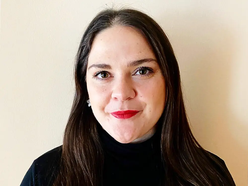 Náborová partnerka ze Severní Ameriky v černém tričku stojí před světle béžovým pozadím a sdílí rady, jak si vybudovat úspěšnou kariéru.